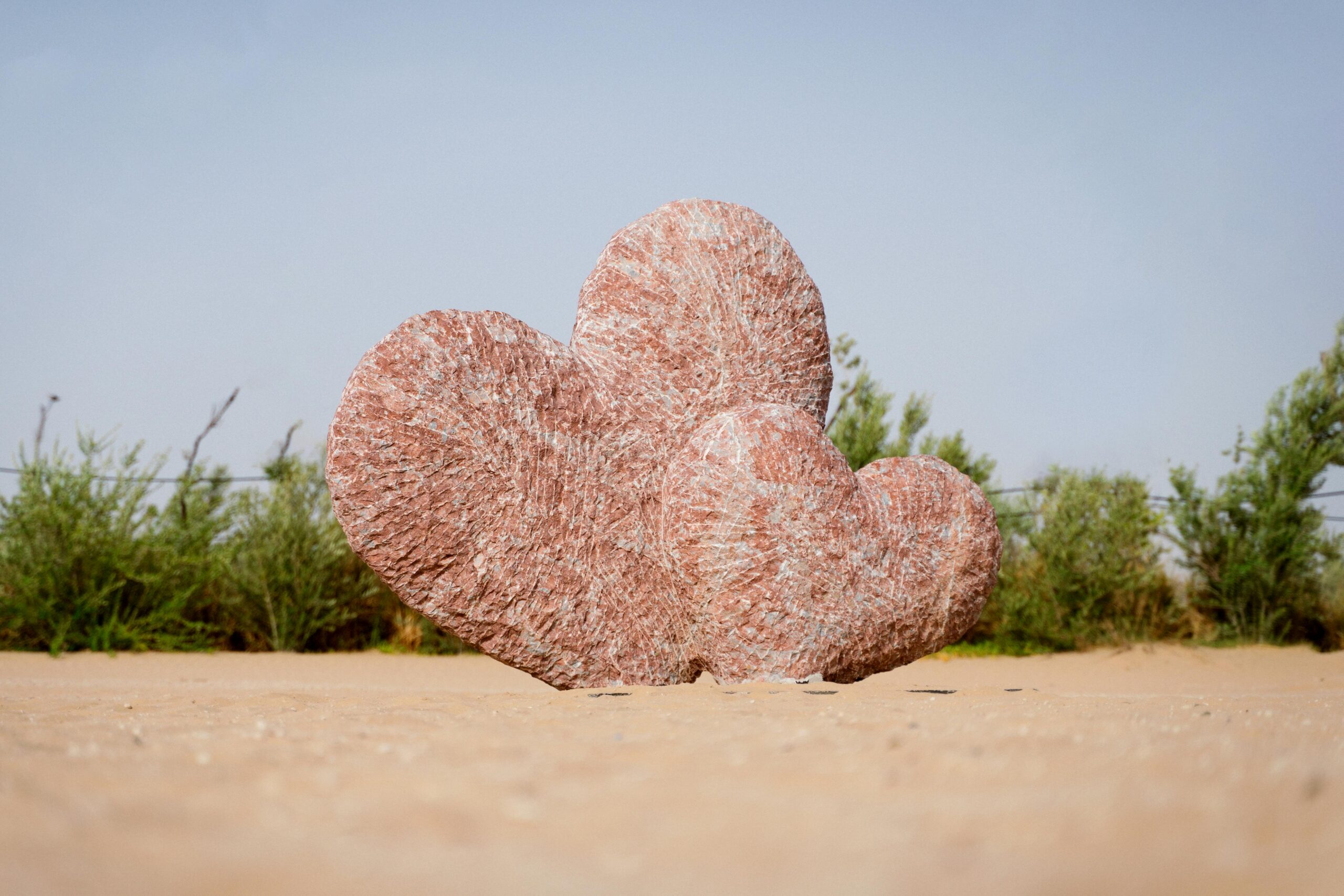 Unique heart-shaped rock formations in the Dubai desert with greenery in the background.